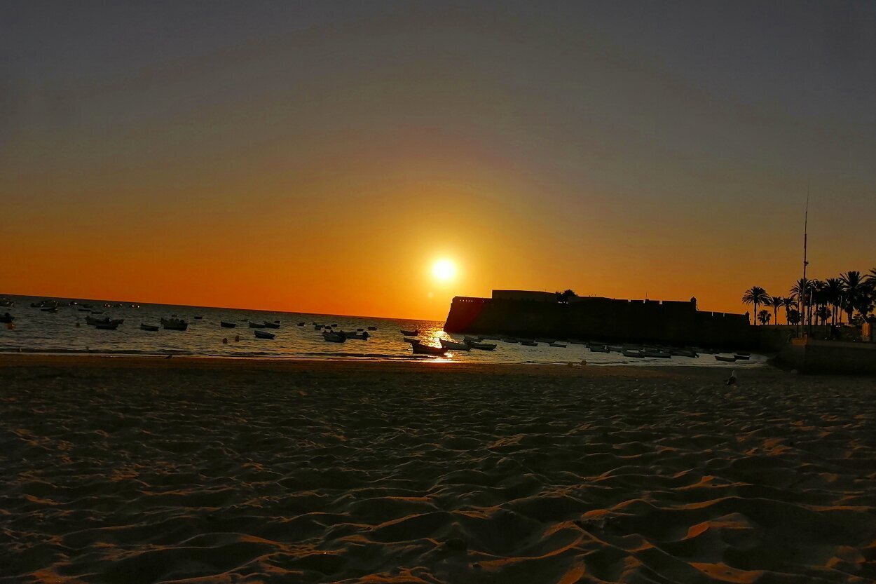 Atardecer desde la Playa de La Caleta, con el Castillo de Santa Catalina de fondo